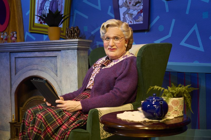 Mrs doubtfire sitting in a chair looking at camera